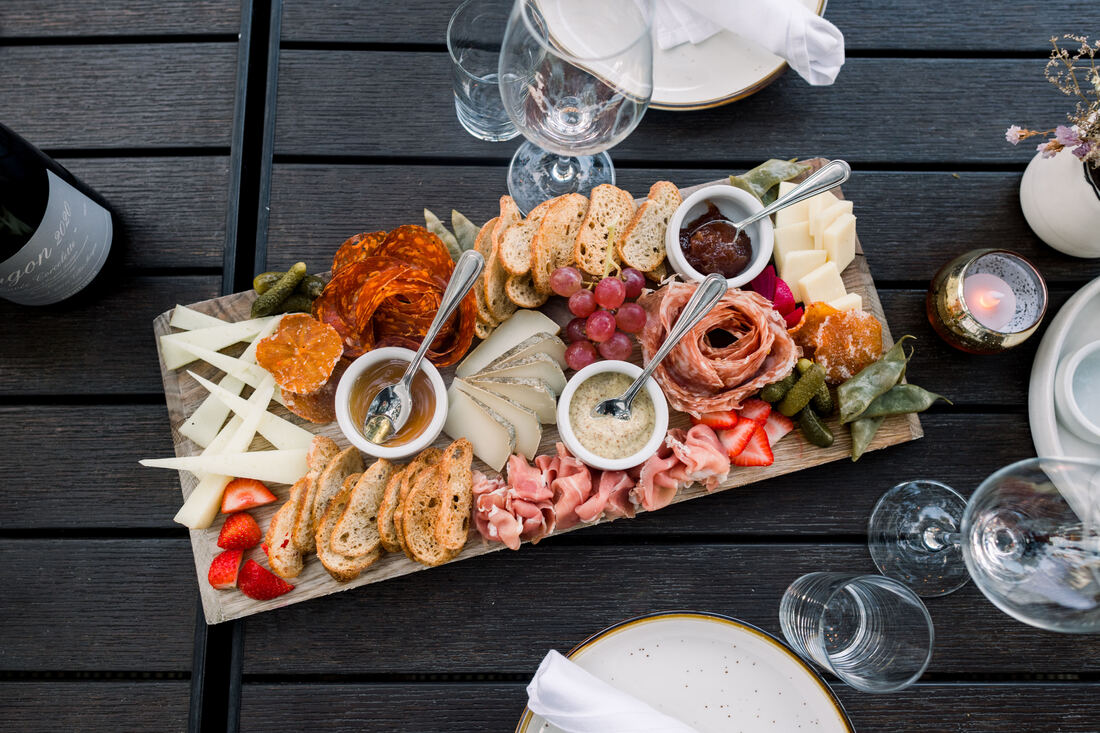 Composed charcuterie and cheese board with house mustard, jam and seasonal fruit