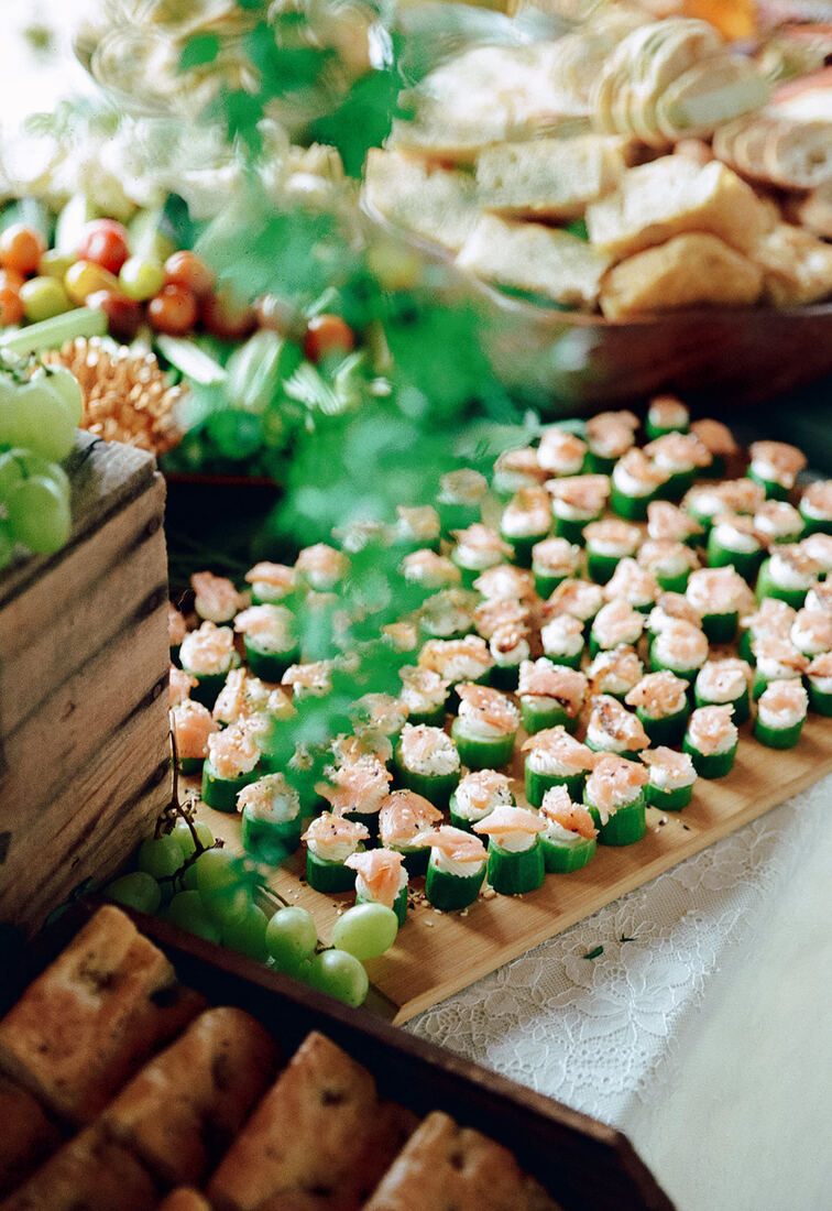Cucumber bites with whipped cheese and smoked salmon on a wooden serving board