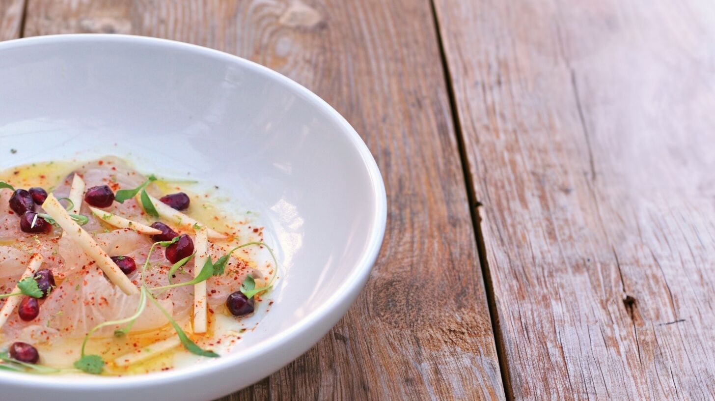 Kampachi crudo plated with pomegranate, apple and chili oil, one of Chef Sheyna's specialty dishes